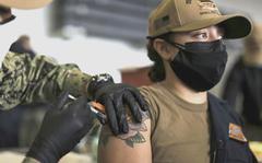 A U.S. Navy sailor receives a COVID-19 booster shot in the hangar bay of the aircraft carrier USS Abraham Lincoln in San Diego on Dec. 28, 2021.