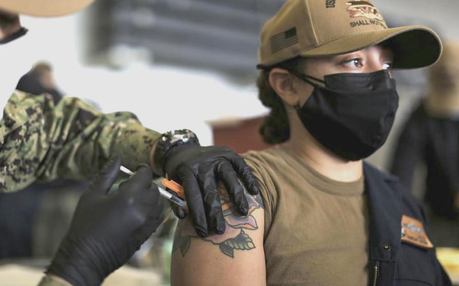 A sailor receives a COVID-19 booster shot in the hangar bay of the aircraft carrier USS Abraham Lincoln in San Diego on Dec. 28, 2021.