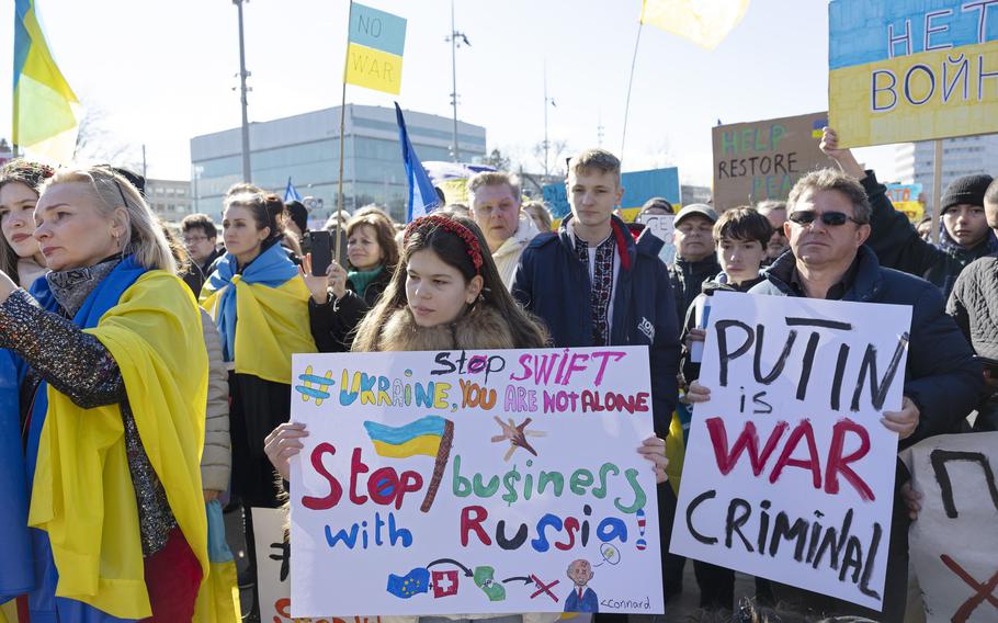 Demonstrators in Geneva, Switzerland, on Saturday, February 26, 2022, hold placards while protesting Russia’s massive military operation against Ukraine. A sign demands to stop SWIFT for Russia’s business. 