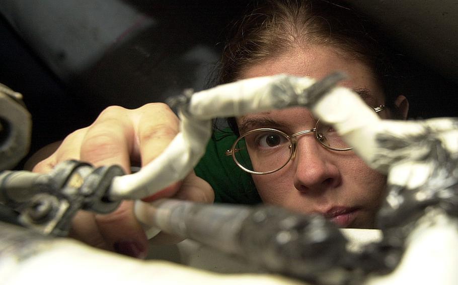 Petty Officer 3rd Class Laura Bailey, assigned to VFA-154, applies sealant to aircraft equipment in the USS Kitty Hawk’s hangar bay Tuesday, April 16, 2002, prior to the start of that day’s flight operations.
