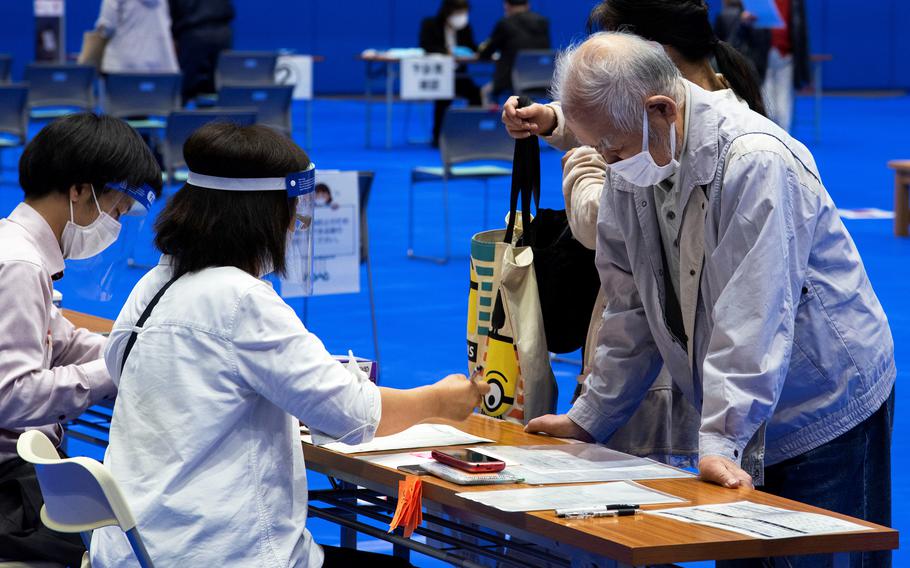 A resident of Iwakuni, Japan, speaks with a medical worker before his COVID-19 vaccination at Atago Sports Complex, which is shared with the U.S. military, Thursday, May 20, 2021. 