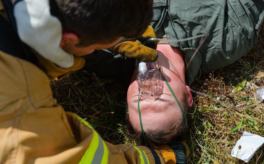 A firefighter with the 86th Civil Engineer Group places an oxygen mask on Tech. Sgt. James Bennett, who played the victim of an aircraft crash at Ramstein Air Base, Germany, July 26, 2022. Bennett is a radar, airfield and weather systems technician with the 424th Air Base Squadron.