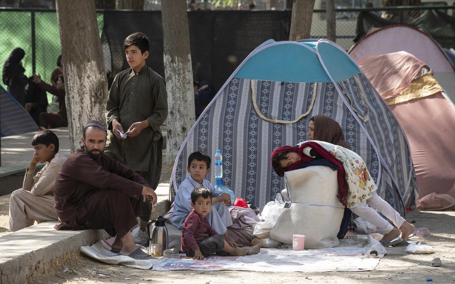 A family waits at a Kabul park on Friday, Aug. 13, 2021. Thousands of Afghans have fled to the Afghan capital after the Taliban began overtaking cities across the county during the past week. 