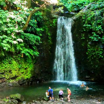 Hikers cool off beneath the Salto do Prego waterfall on São Miguel. 