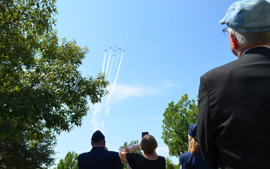 Planes fly overhead as people watch.