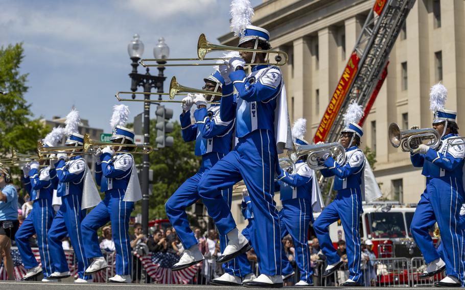 Trombone players and French Horn players march, wearing their blue band uniforms.