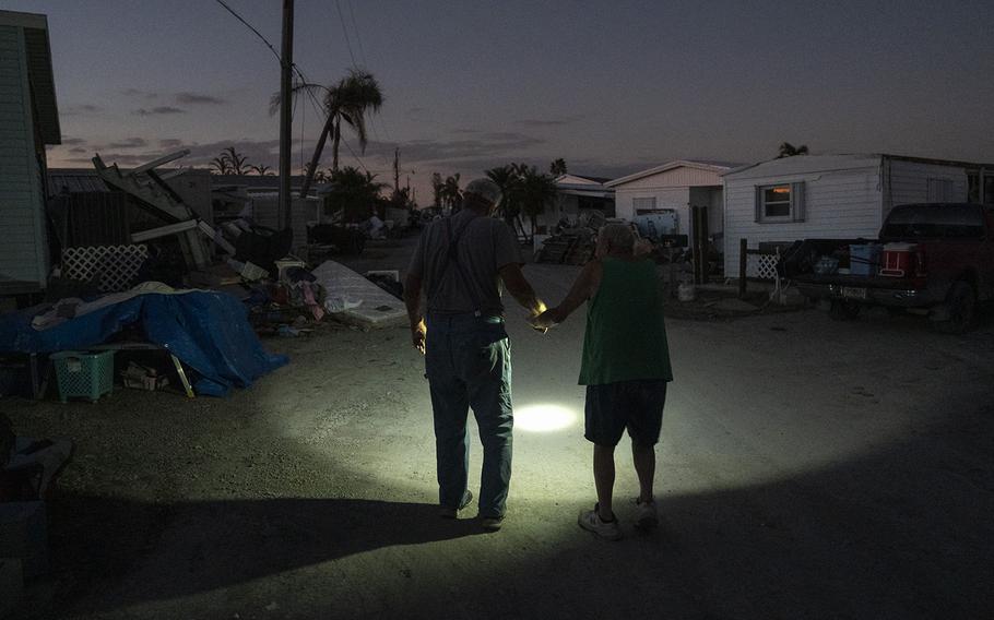 Charlie Whitehead, left, helps his 84-year-old neighbor Leslie Pickett down the street of their mobile home community in San Carlos Island, Florida. 