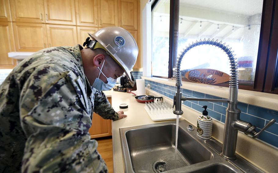 A sailor inspects running water at a home on Joint Base Pearl Harbor-Hickam, Hawaii, on Feb. 18, 2022, in response to a jet fuel spill that contaminated the area’s drinking water. 