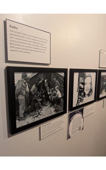 Framed black-and-white photographs and placards adorn a wall.
