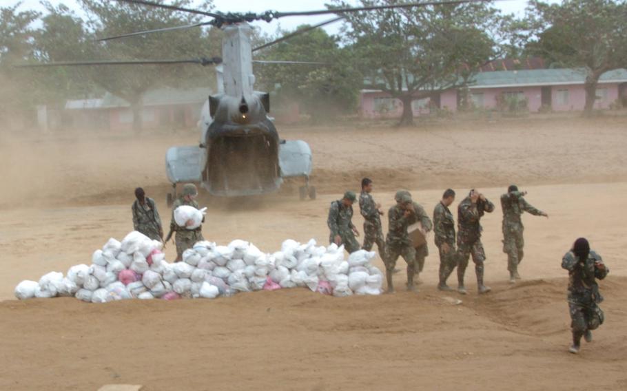 Members of the Armed Forces of the Philippines offload relief aid from a Marine CH-46 E at Infanta, Luzon. The aid was later distributed by the AFP and aid workers.