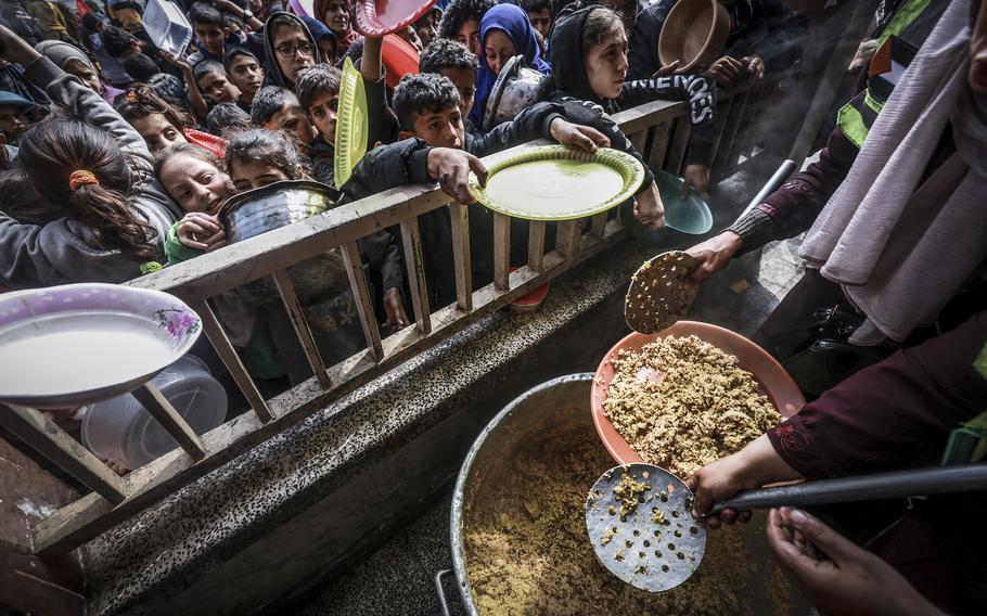 Displaced Palestinian children gather to receive food at a government school in Rafah in the southern Gaza Strip on Feb. 19, 2024.