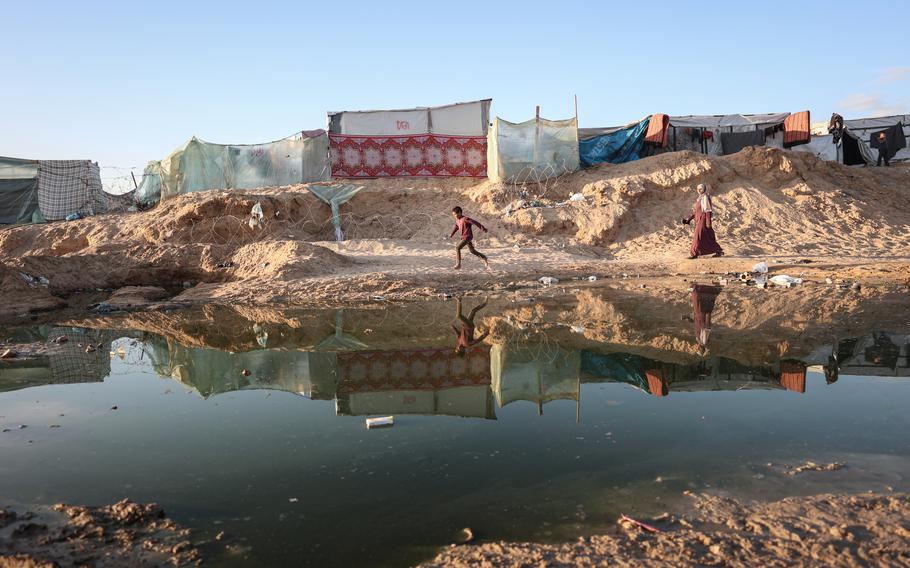 A child runs alongside sewage near tents for displaced people on the Egyptian-Palestinian border, south of Rafah, on Jan. 21, 2024.