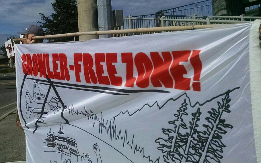 Protesters stand on a sidewalk holding a banner reading “Growler-Free Zone!”