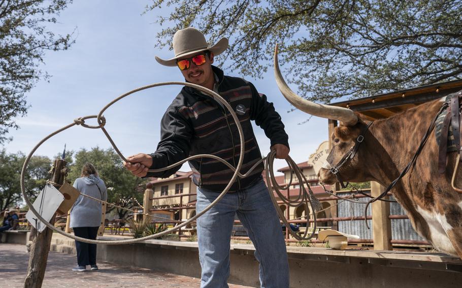 Tourists explore the Fort Worth Stockyards as Ian Garza practices with a lasso. The historic area has shopping and dining and still hosts cattle drives. 