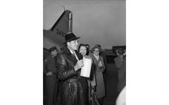 Actor Errol Flynn - a massive German beer stein in hand - greets gathered journalists, photographers and onlookers on the tarmac at Rhein Main airport February 4, 1954. The actor has come to Germany together with wife, actress Patrice Wymore and New York born Puerto Rican actress, dancer and comedienne Olga San Juan to perform at a benefit show for the March of Dimes organization at the Casino at the EUCOM Hq in Frankfurt that same evening. [cg]