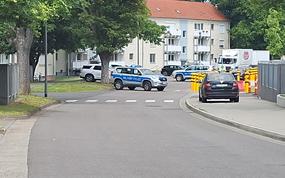 Military police vehicles block traffic near an apartment building.