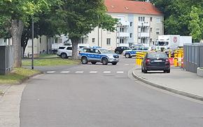 Military police vehicles block traffic near an apartment building.