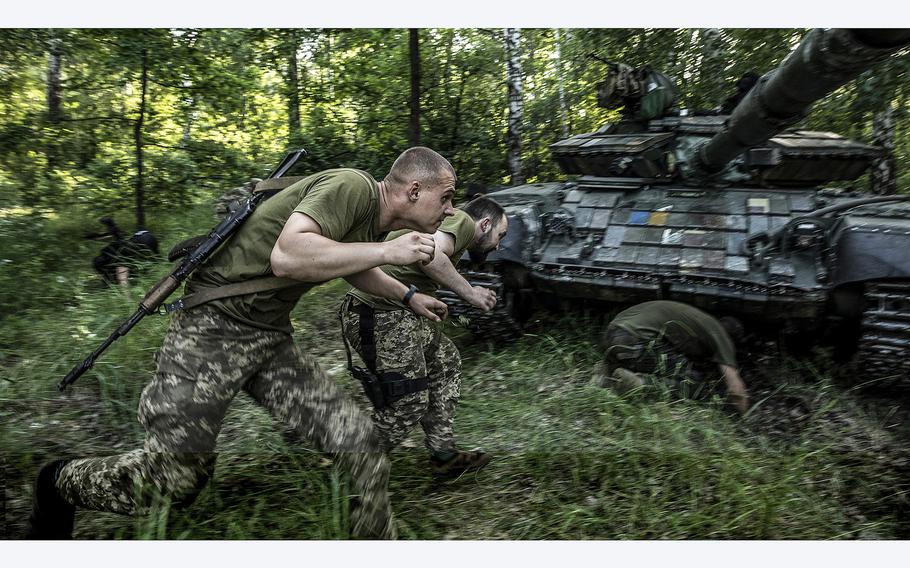 Ukrainian soldiers scramble to take cover under a tank during an intense bombardment of a suspected Russian cluster shelling that targeted their artillery position near a road that leads to the eastern city of Lyman, Ukraine, on June 2, 2022. Russia has officially announced that they now control eastern Ukraine’s strategic town of Lyman in Donbas. 