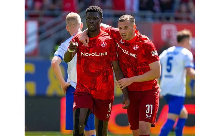 Two men walk together on a soccer field