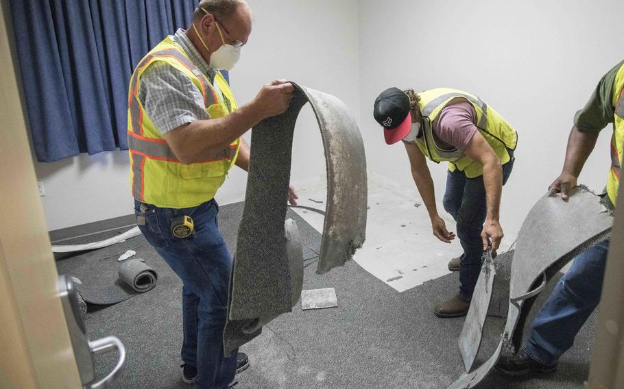 Workers remove carpet from a dorm room impacted by mold Aug. 1, 2019, at Joint Base San Antonio-Lackland, Texas. A Government Accountability Office reported observed barracks at seven of 10 military installations visited that required significant improvements.