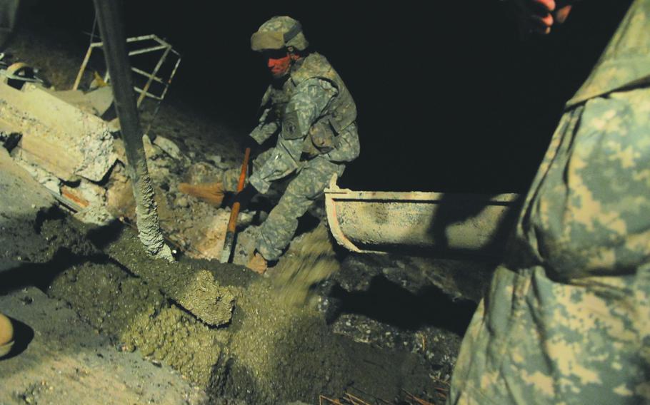 Soldiers with the 19th Engineer Battalion spread concrete in a fresh roadside bomb crater near Tikrit, Iraq. If left unrepaired, the craters provide hiding places for explosives and driving hazards for motor vehicles.