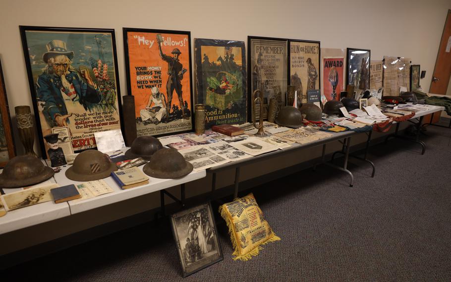 Posters, helmets and other assorted items adorn a row of tables next to a wall.