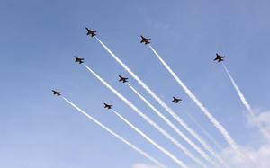 Jets fly across a blue sky.