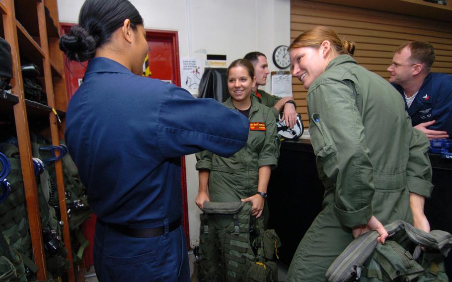 Sailors help each other get into their flight gear