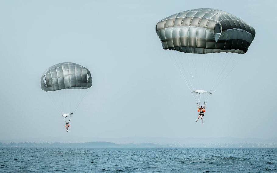Two paratroopers gliding into a lake.