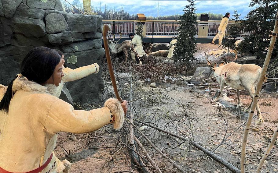 A diorama shows a statue of a native person and several lifelike deer.