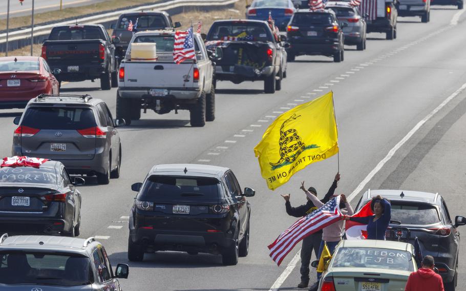 People on the side of the road watch as trucks and other vehicles with the People Convoy of Truckers, protesting mandates and other issues, head south on Interstate I-270 Sunday, March 6, 2022, in Frederick, Md., toward the Washington Beltway.
