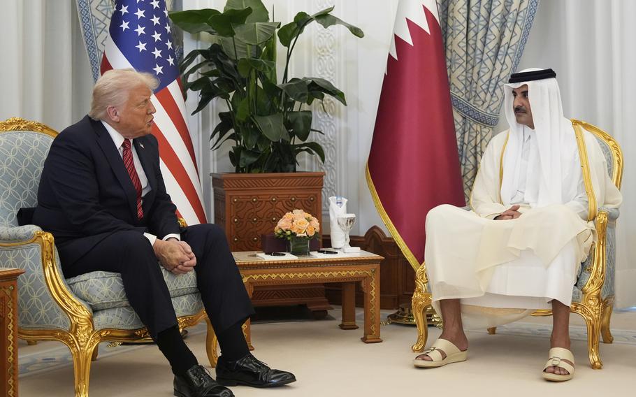 Trump and al Thani sit opposite each other, with U.S. and Qatar flags behind them.