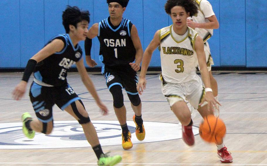 Humphreys' Brandon Howell drives upcourt against Osan's R.J. Jones during Friday's DODEA-Korea boys basketball game. The Blackhawks won the Korea inter-division battle 59-50.