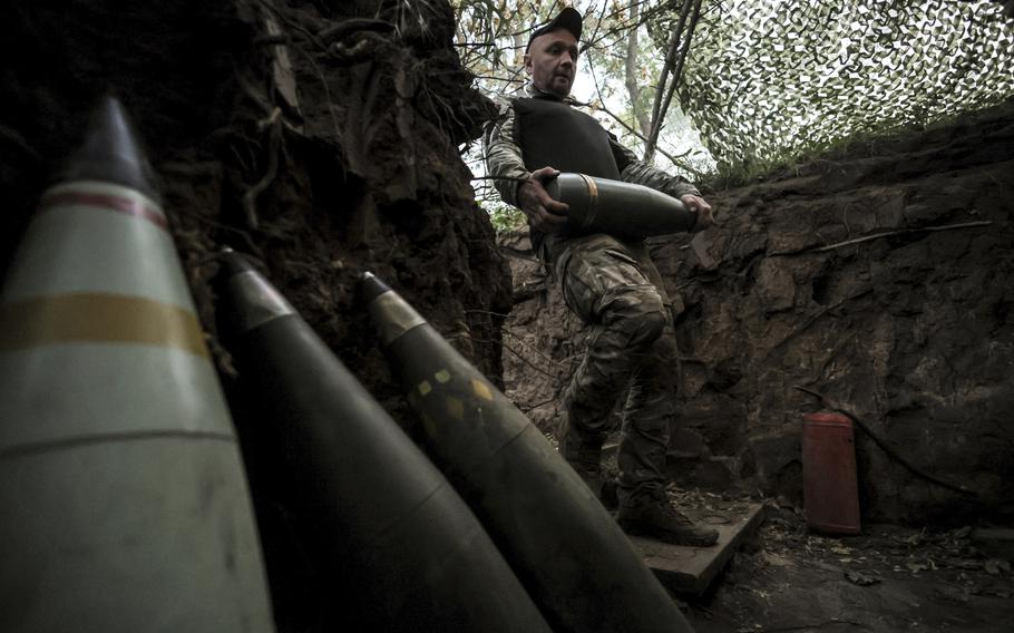 Ukrainian soldier standing next to a few shells.