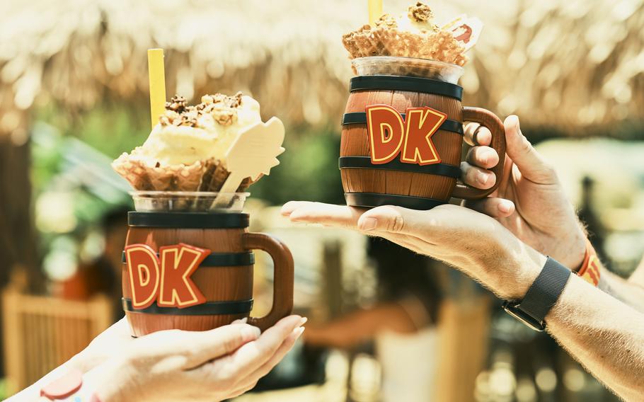 Guests hold up souvenir Donkey Kong cups. 
