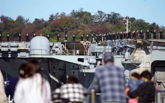 Family members gather along the base shoreline to watch the aircraft carrier USS Ronald Reagan return to Yokosuka Naval Base, Japan, Sunday, Nov. 19, 2023. 