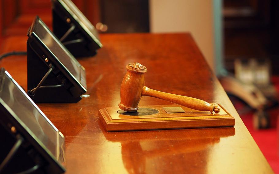 A gavel sits on a block in a courtroom. 