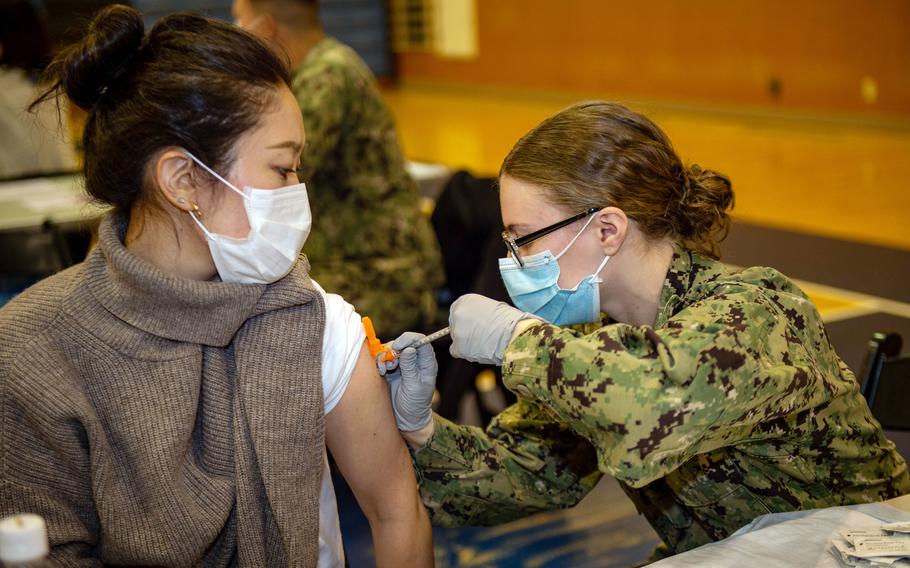 Petty Officer 3rd Class Courtney Minchew, a hospital corpsman assigned to the aircraft carrier USS Ronald Reagan, administers a COVID-19 vaccination booster to a Japanese worker at Yokosuka Naval Base, Japan, Friday, Jan. 28, 2022.