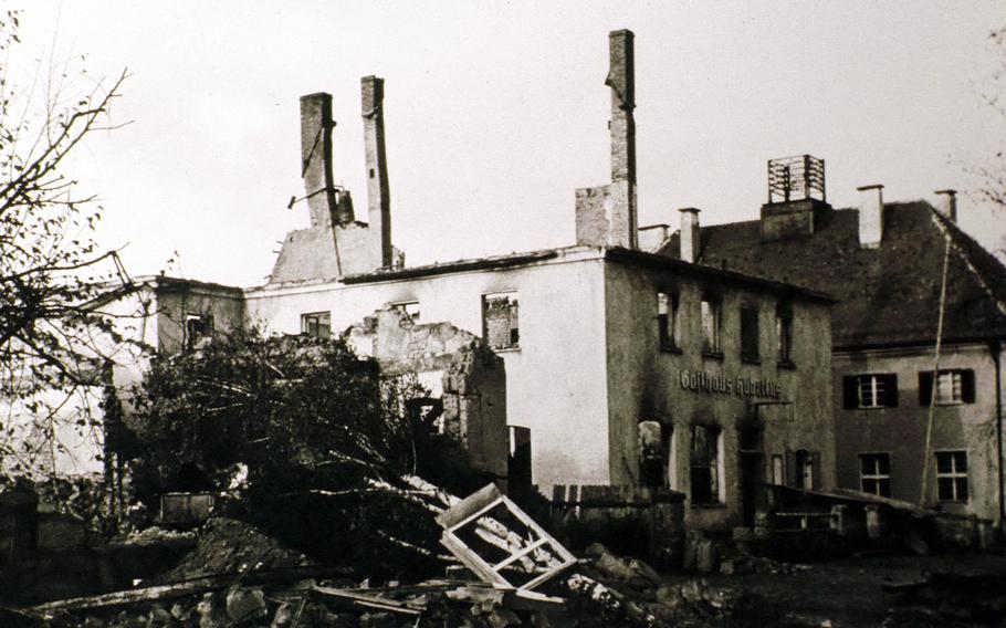 A black and white photo of a post office with three chimney stacks standing mostly untouched next to ruins of other buildings 