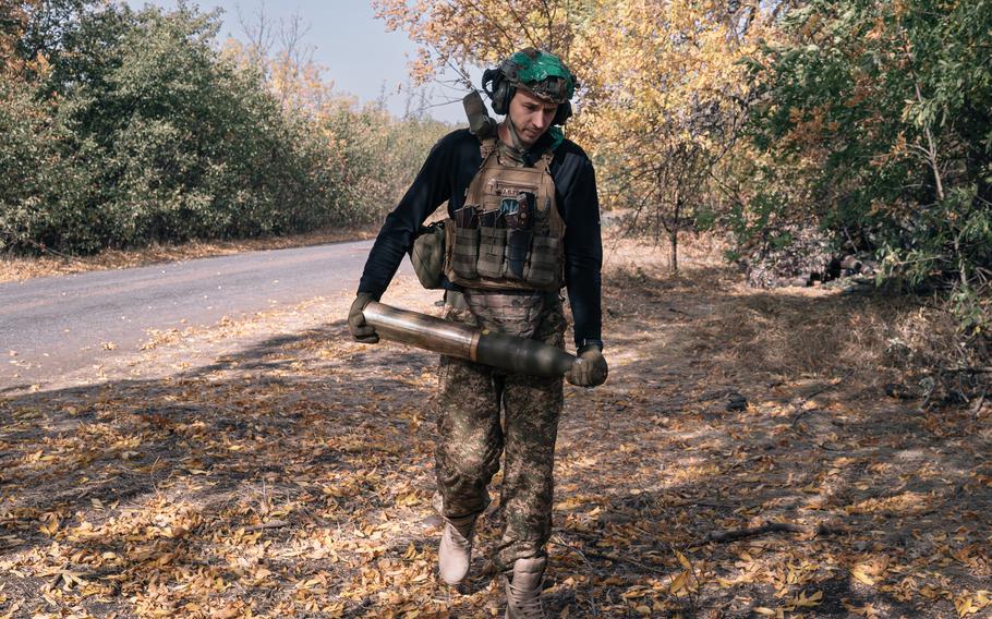 A Ukraine soldier with an artillery shell.