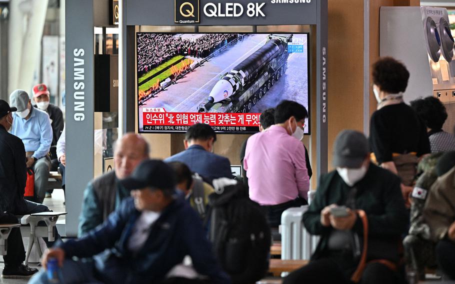People watch a television screen showing a news broadcast of a military parade held in Pyongyang to commemorate the 90th founding anniversary of the Korean People's Revolutionary Army, at a railway station in Seoul on April 26, 2022. 