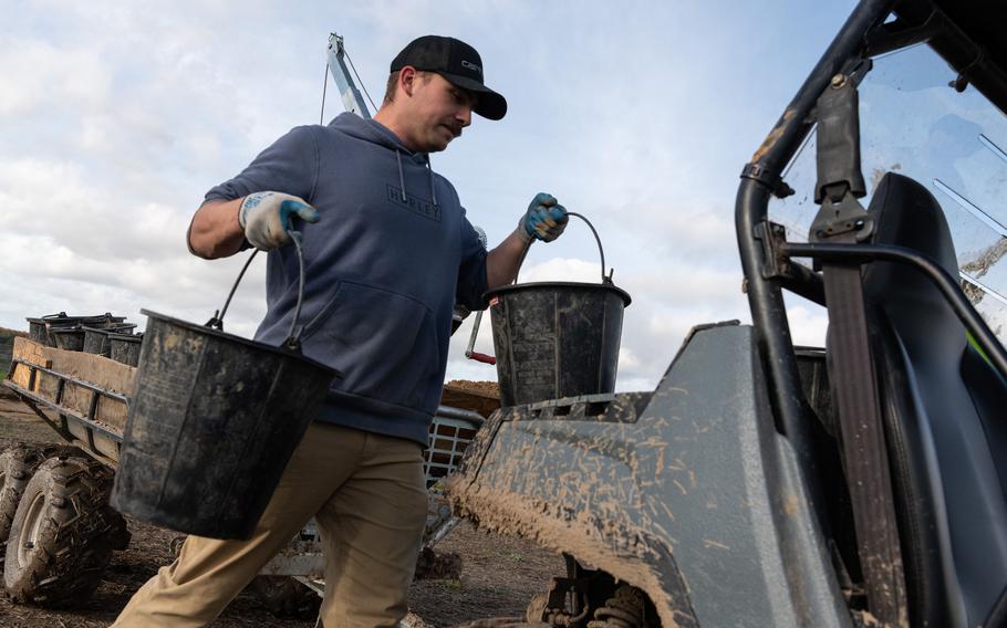 Army Spc. Taven Kimmel, of the 2nd Cavalry Regiment, loads buckets of extracted soil onto a trailer in Wistedt, Germany, Oct. 30, 2023. The buckets will be moved to a sorting area on the site for examination. 