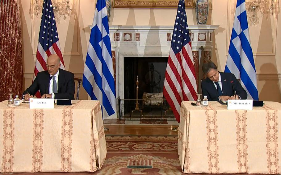 In a screenshot from Twitter, Secretary of State Antony Blinken, right, and his Greek counterpart Nikos Dendias sign the renewal of the U.S.-Greece Mutual Defense Cooperation Agreement after talks in Washington, Oct. 14, 2021.