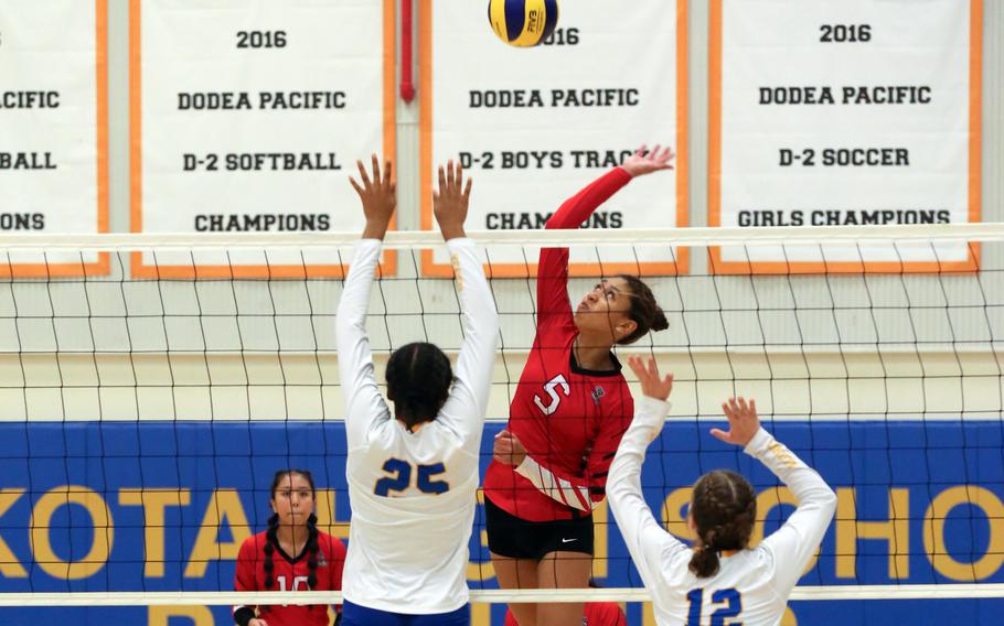 E.J. King's Mila Nishimura-Reed skies to spike against Yokota's Trinity Stegall and Kayla Bogdan. Nishimura-Reed and Stegall were named to the Far East Division II girls volleyball tournament All-Tournament team.