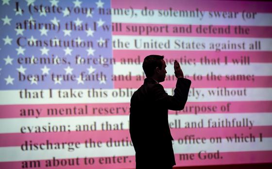 The Oath of Office is projected on a screen behind an ROTC cadet as he takes the Oath at Clemson University. Clemson's Army and Air Force ROTC units held a joint ceremony to commission 33 second lieutenants into military service, May 11, 2022. Eighteen students received comissions into the Army, 14 into the Air Force, and one received a commission into the Space Force. After the ceremony the new officers recieved their first salutes during a Silver Dollar Salute ceremony in Military Heritage Plaza. (Photo by Ken Scar)
