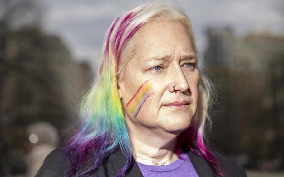 A person with hair dyed several colors and colored lines painted on her face.