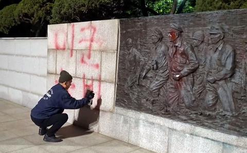 A man writes “Deport U.S. troops” with spray paint near a statue of Gen. Douglas MacArthur at Freedom Park in Incheon, South Korea, Thursday, April 28, 2022. The image is from a video posted to Facebook by Peace Agreement Movement Headquarters, an anti-U.S. military group.