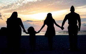 A Marine Corps family is silhouetted on a beach. According to a new Defense Department survey, more than half of service member spouses are unhappy with military life due to frustrations over frequent moves and difficulties finding employment. 