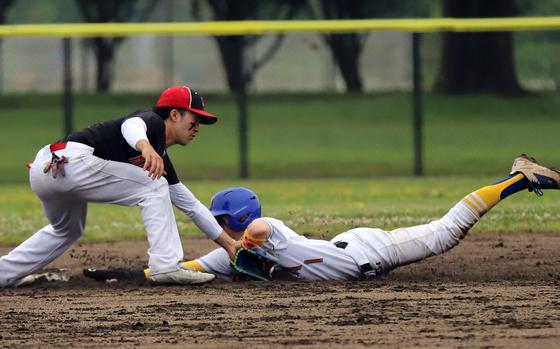 Yokota's Joshua Low slides safely into second base as Kinnick's Keanu Servan can't field the ball.