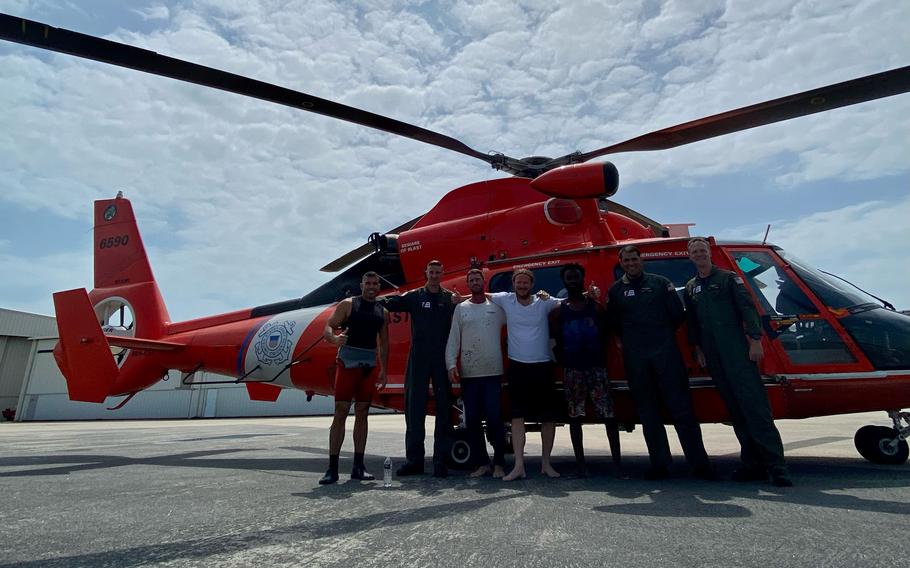A Coast Guard Air Station MH-65 Dolphin helicopter crew poses with three rescued men after their boat sunk near Dry Tortugas National Park, Florida, April 30, 2023.